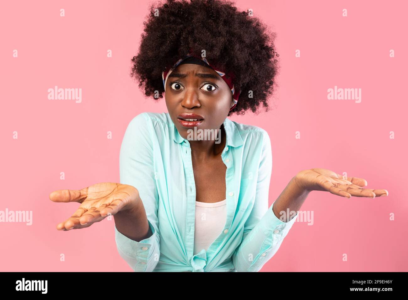 Puzzled African Lady Shrugging Shoulders Standing Over Pink Background Stock Photo