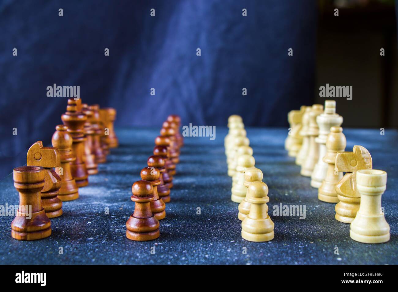 A side view of wooden chess figures in starting position on a blue ...