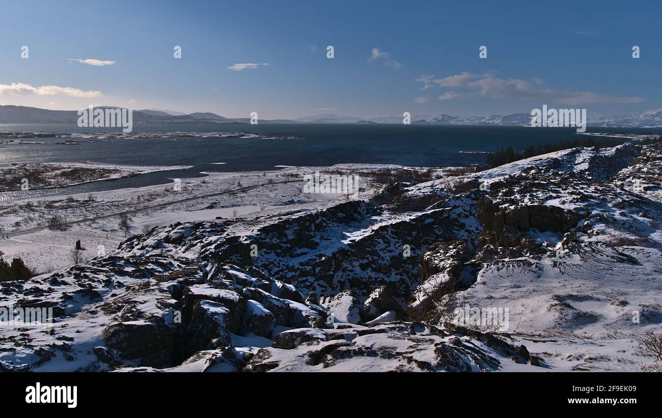 Stunning panoramic view of blue colored lake Þingvallavatn, largest natural lake of Iceland, and rugged, snow-covered mountains viewed from Þingvellir. Stock Photo