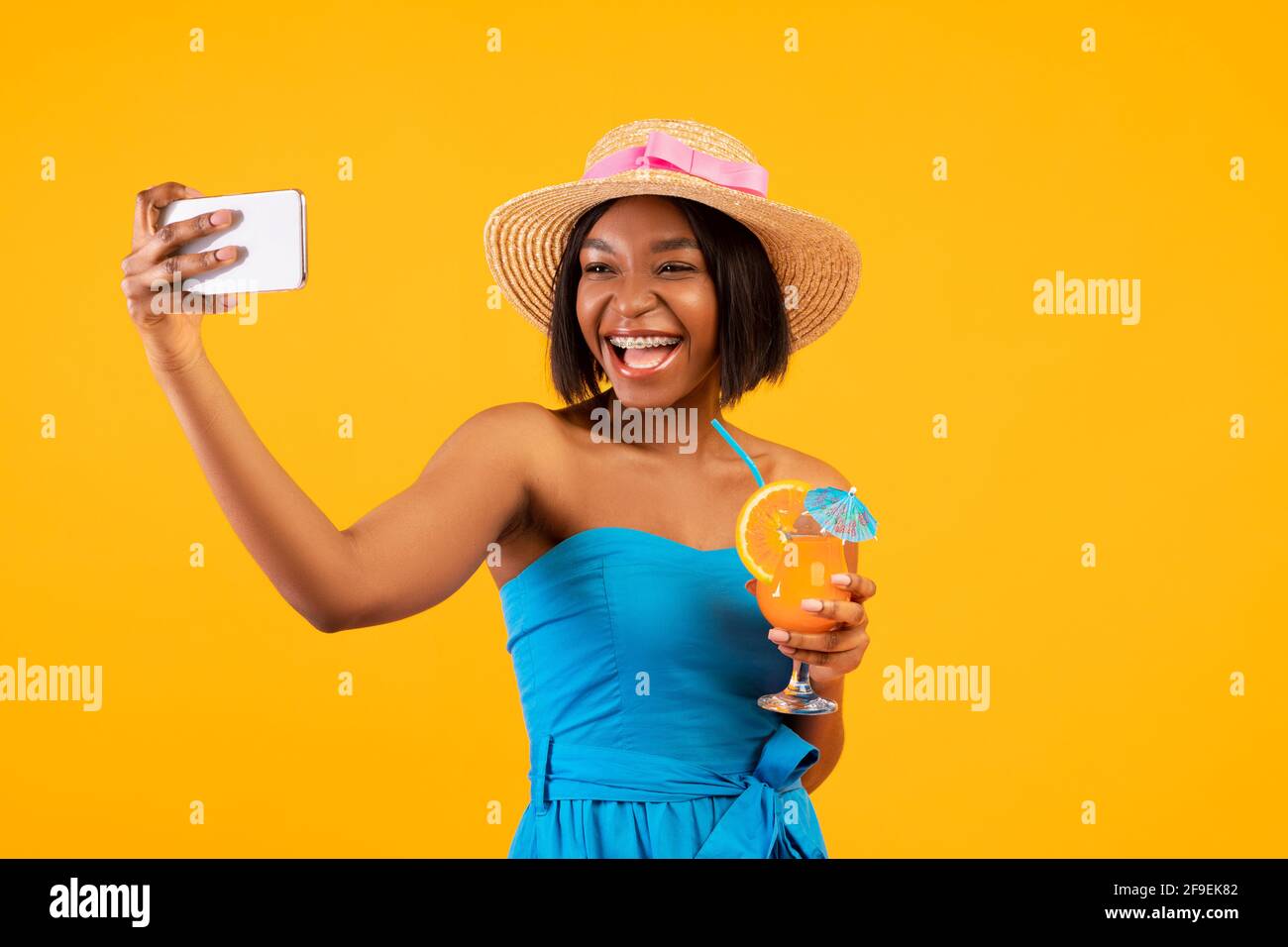 Happy black woman with yummy summer cocktail taking selfie on smartphone  over orange studio background Stock Photo - Alamy, image size:1300x956