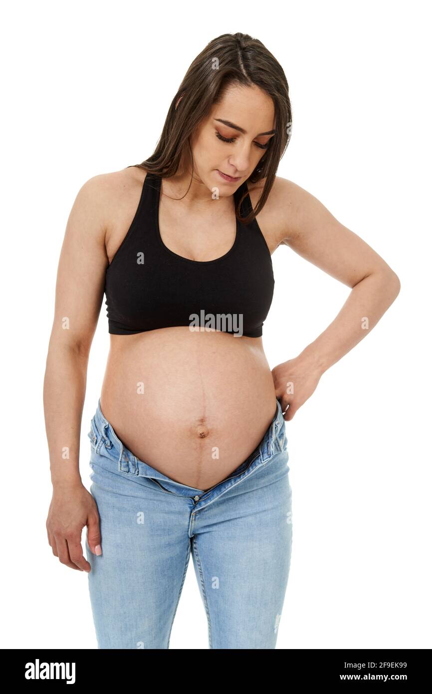 Pregnant woman trying to fit in her too tight jeans, isolated on white  background Stock Photo - Alamy