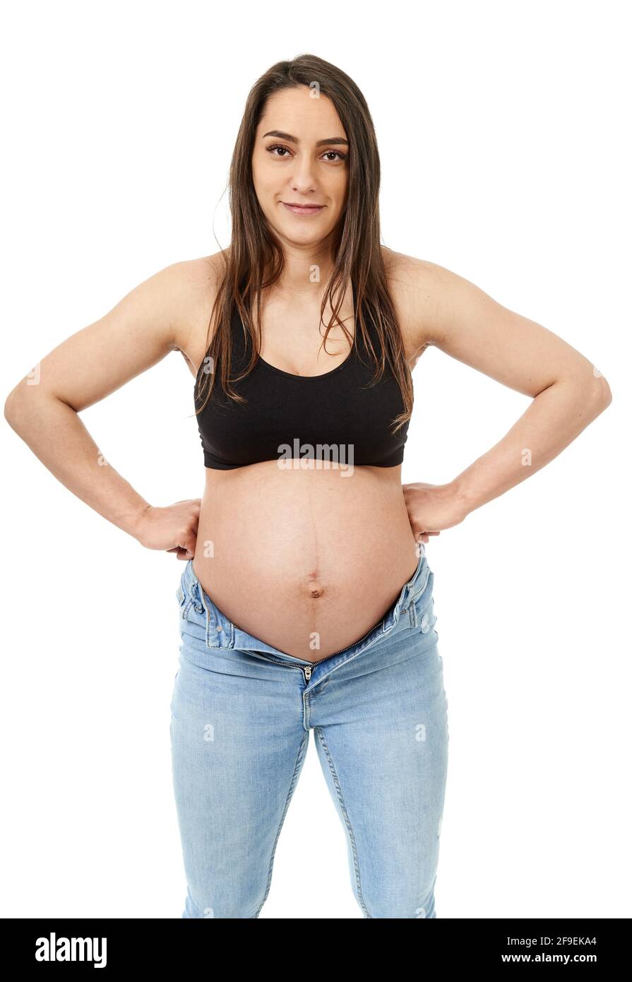 Pregnant woman trying to fit in her too tight jeans, isolated on white  background Stock Photo - Alamy