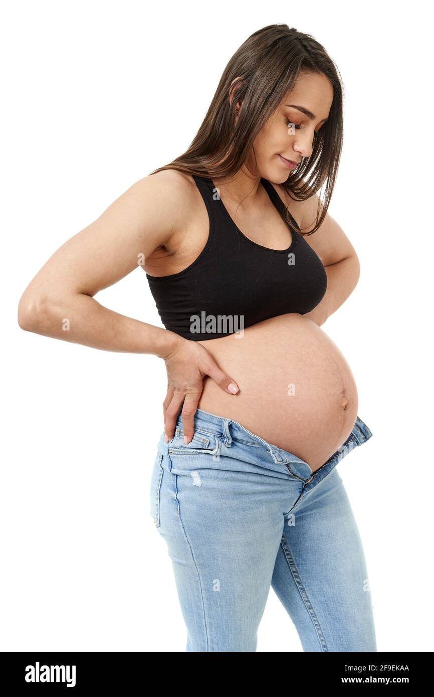 Pregnant woman trying to fit in her too tight jeans, isolated on white  background Stock Photo - Alamy