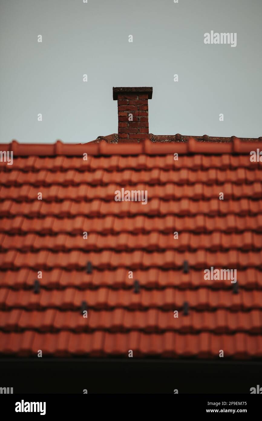 A view of a chimney on a top of the house with a red tile roof Stock Photo