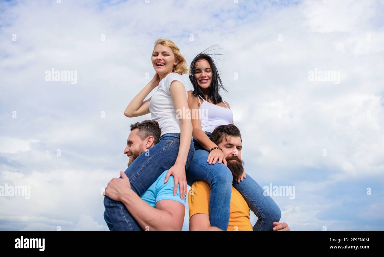 Men carry girlfriends on shoulders. Summer vacation and fun. Couples on