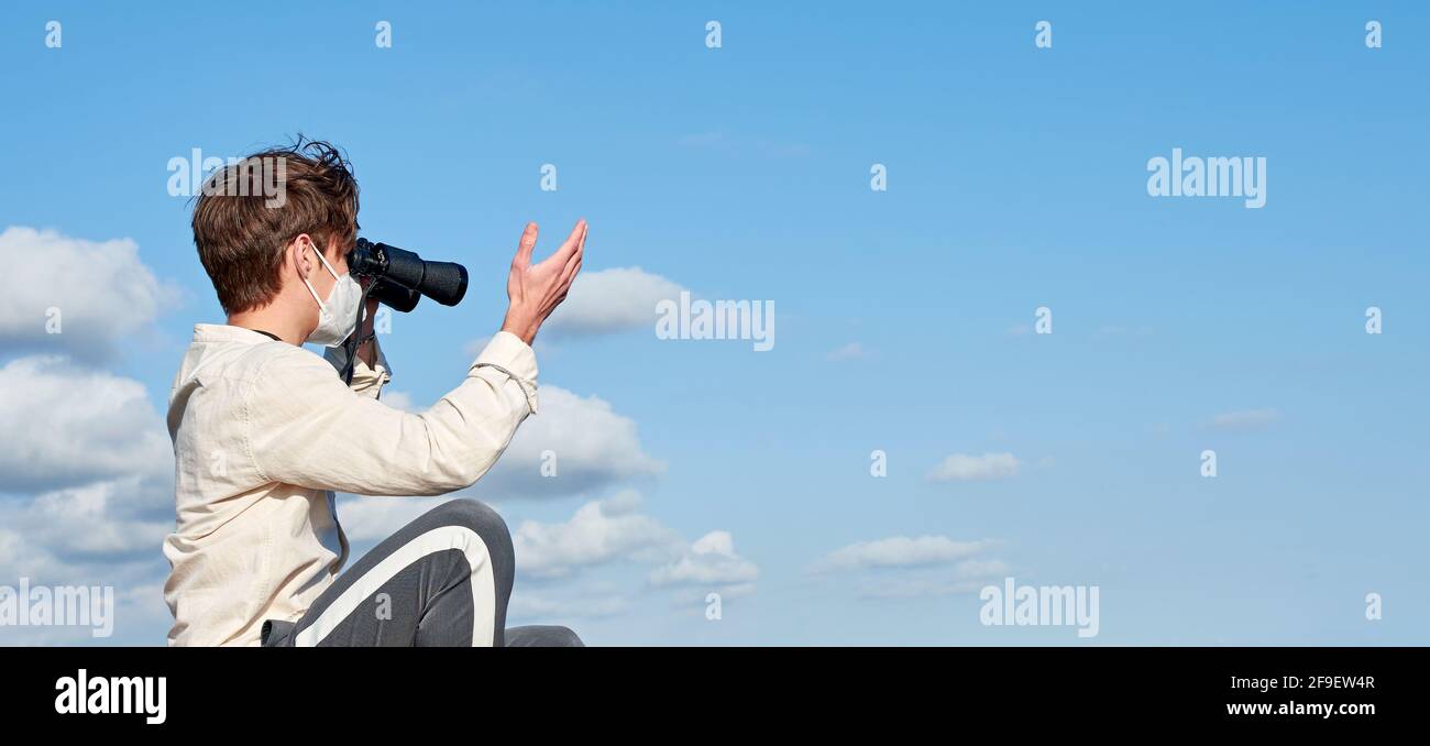 A Spanish adventurous male traveler wearing a mask using binoculars and
