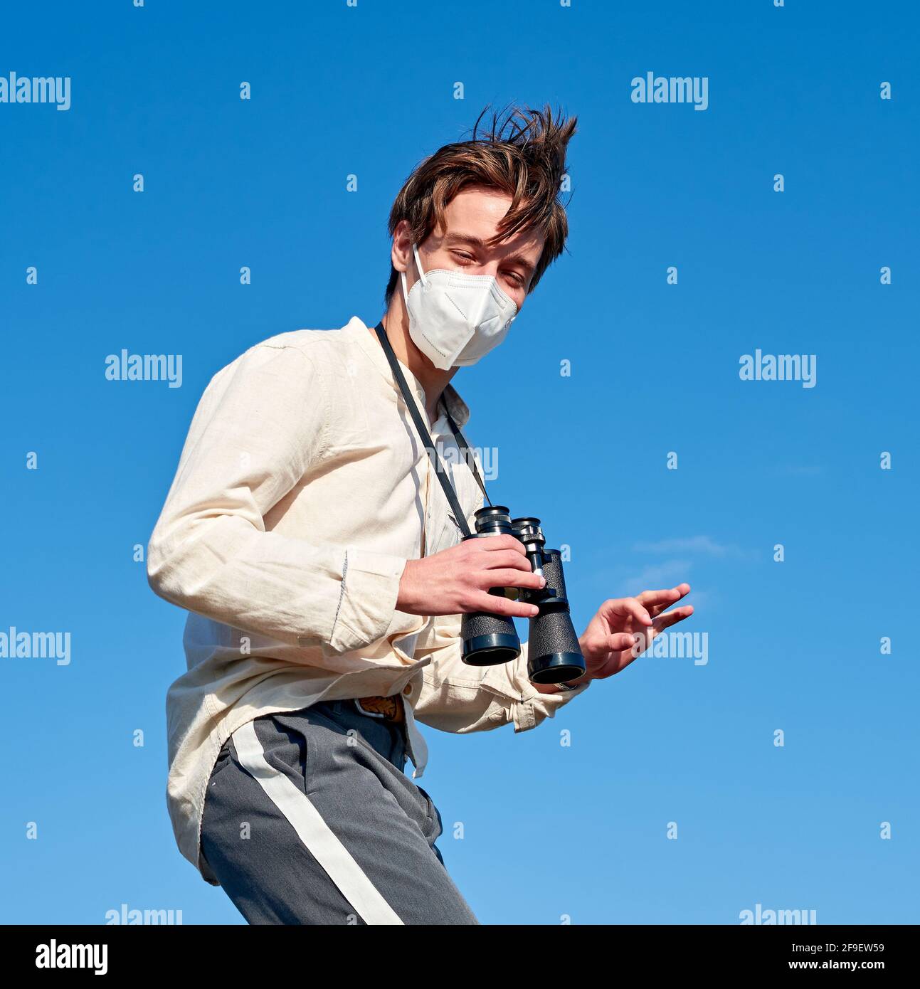 A Spanish adventurous young male traveler wearing a mask holding