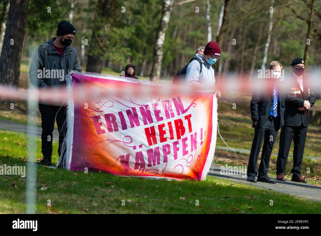 18 April 2021, Lower Saxony, Lohheide/Hörsten: People take part in a remembrance and commemoration ceremony at the Soviet prisoner of war cemetery near Bergen-Belsen with a banner reading 'Remembering means fighting! The Association of Persecutees of the Nazi Regime and the German Trade Union Federation (DGB) commemorated the anniversary of the liberation of the Bergen-Belsen concentration camp. Photo: Philipp Schulze/dpa Stock Photo