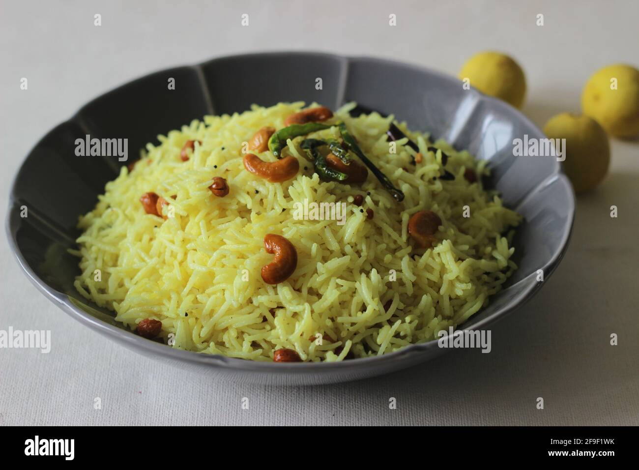 Lemon rice prepared by seasoning cooked rice with mustard seeds, fried lentils, peanuts, cashew nuts, green chillies, dry red chillies, curry leaves, Stock Photo