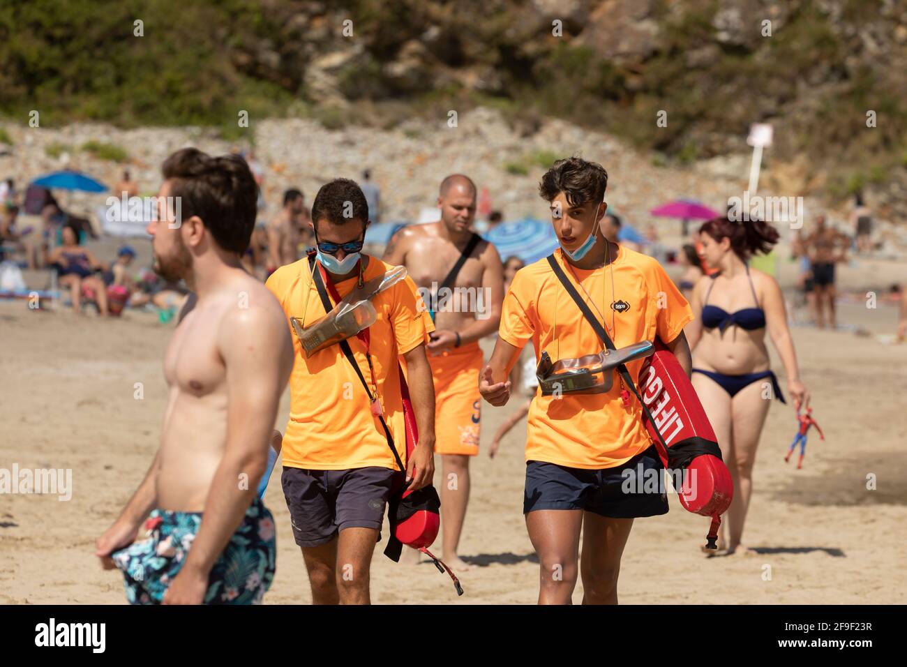 San Pedro de la Ribera, Spain - August 16, 2020: A couple of lifeguards from the public security services walk with the protective face mask on a beac Stock Photo