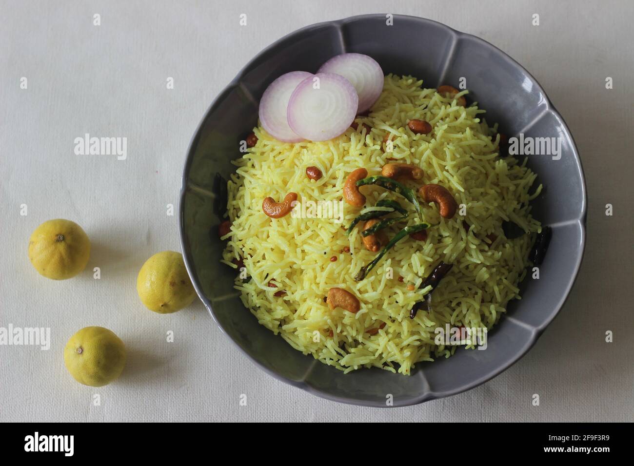 Lemon rice prepared by seasoning cooked rice with mustard seeds, fried lentils, peanuts, cashew nuts, green chillies, dry red chillies, curry leaves, Stock Photo