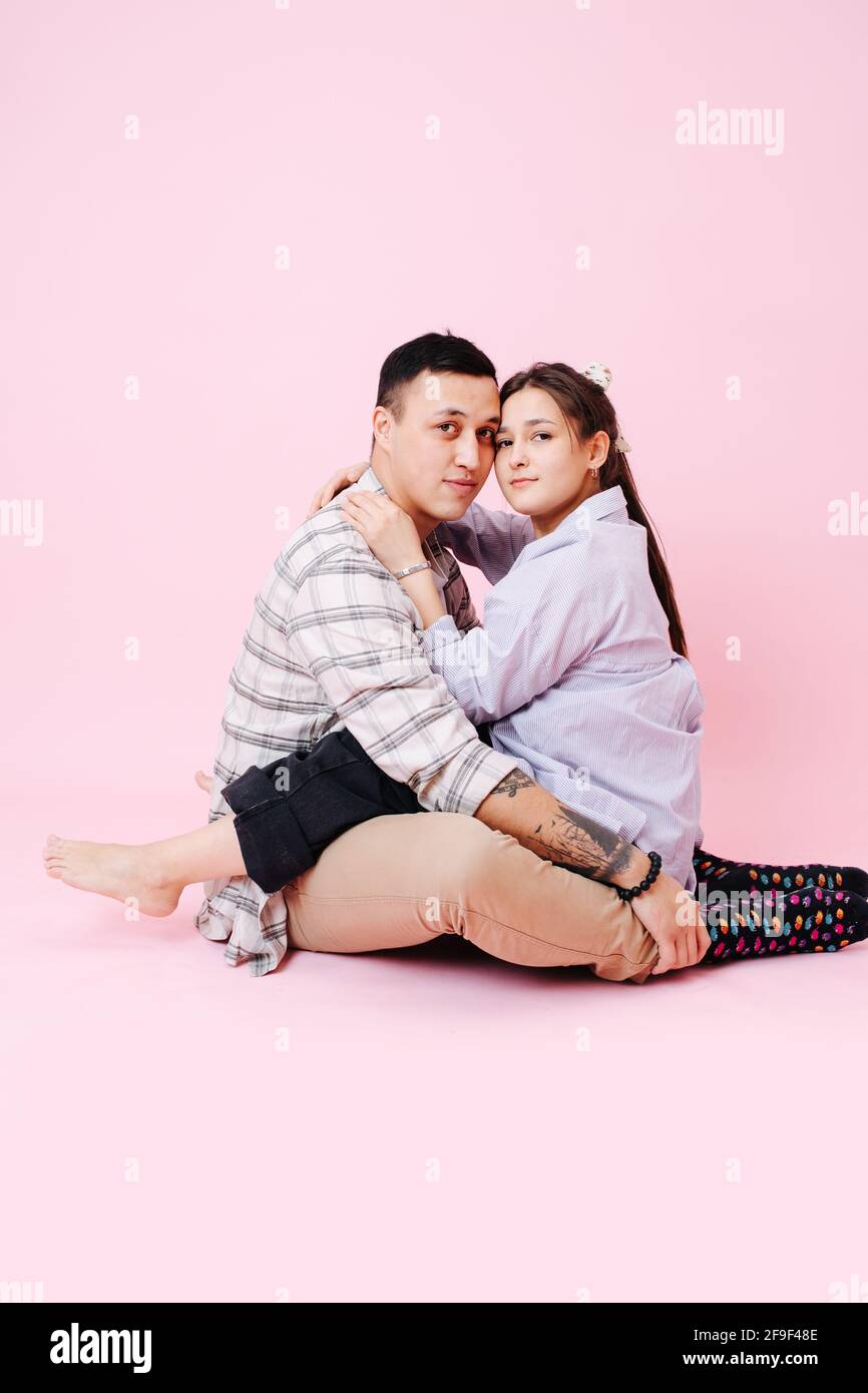 Lovely young couple sitting on the floor, touching heads, looking at ...