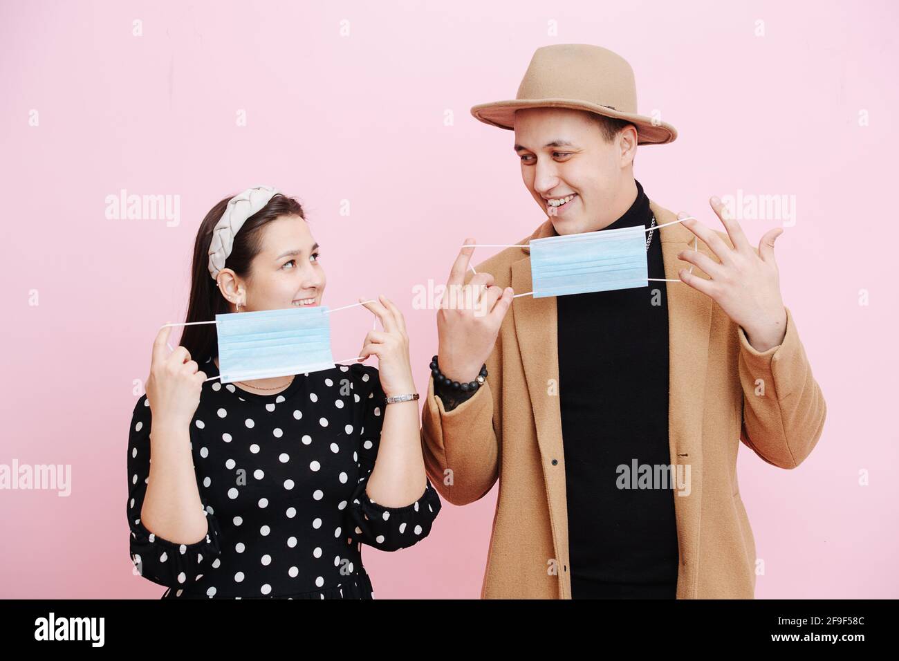 Mindful young couple in love putting on single use medical masks Stock ...