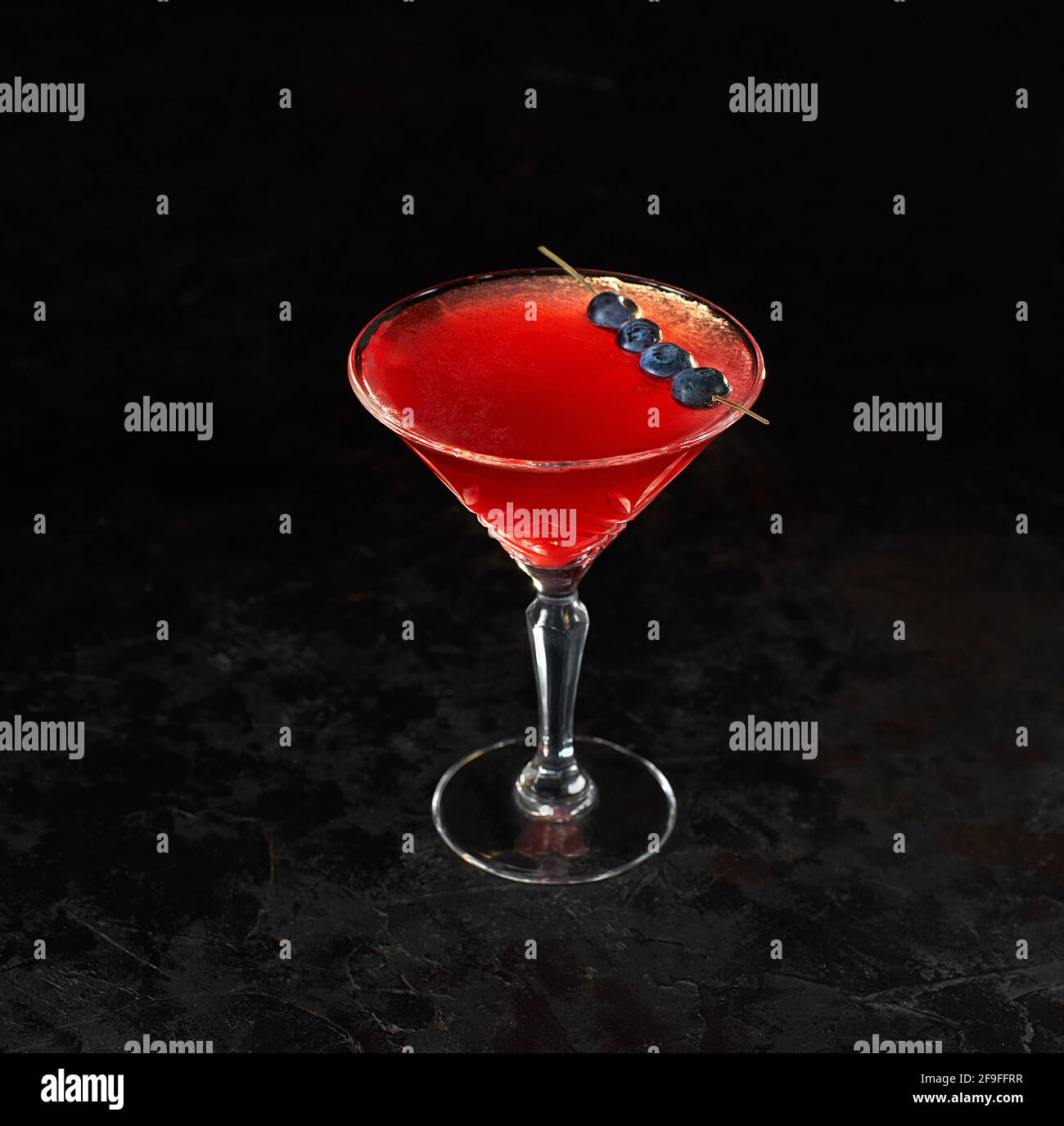 Cosmopolitan cocktail in nice red color in front of a black background ...