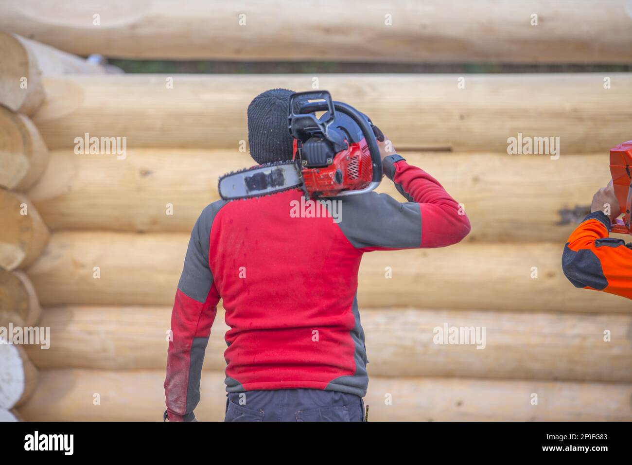 A worker holding a chainsaw in construction area Stock Photo