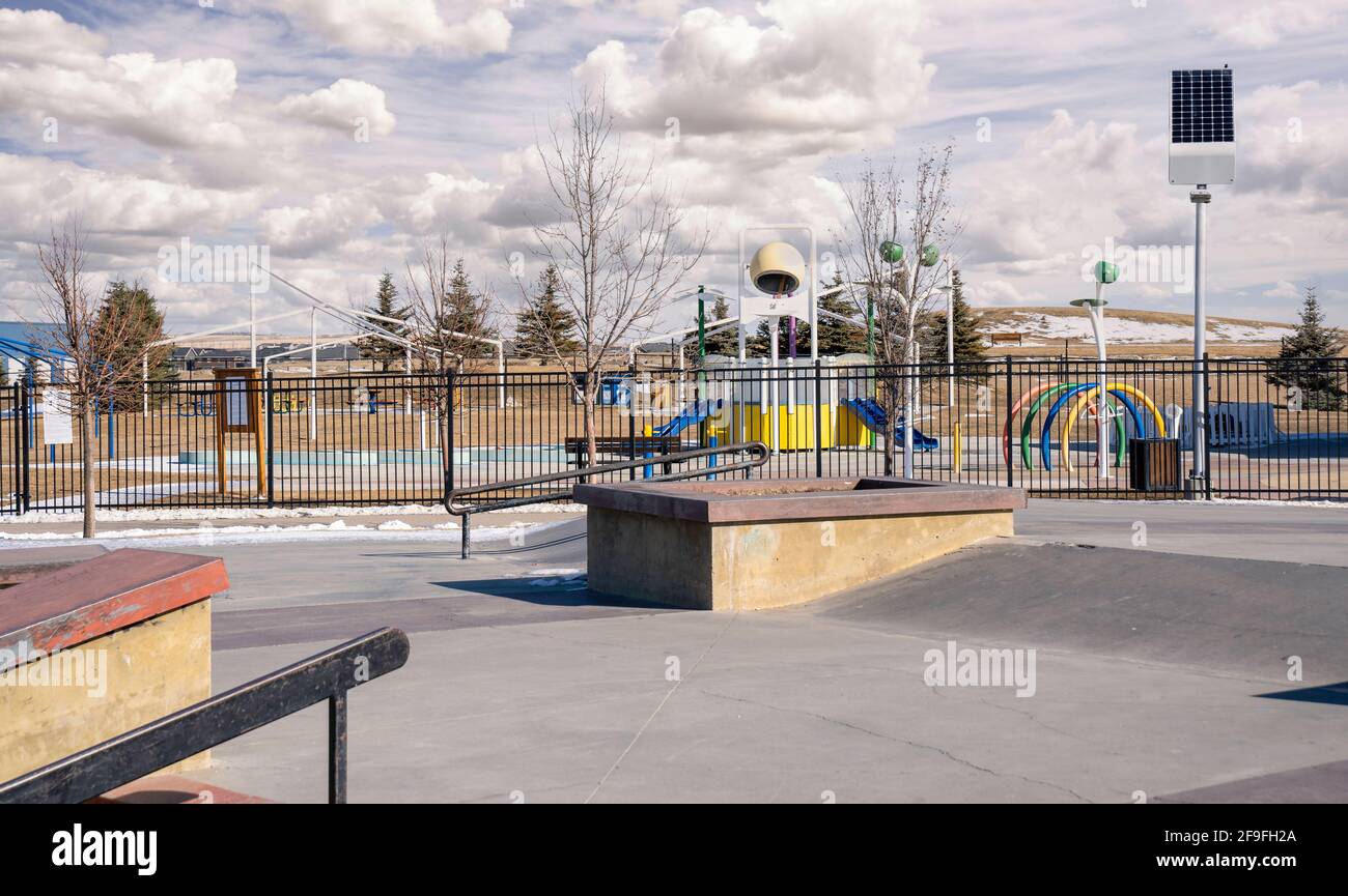 An empty skate park and outdoor splash park with solar panels recharging LED street lights in the urban community of Airdrie Alberta Canada. Stock Photo