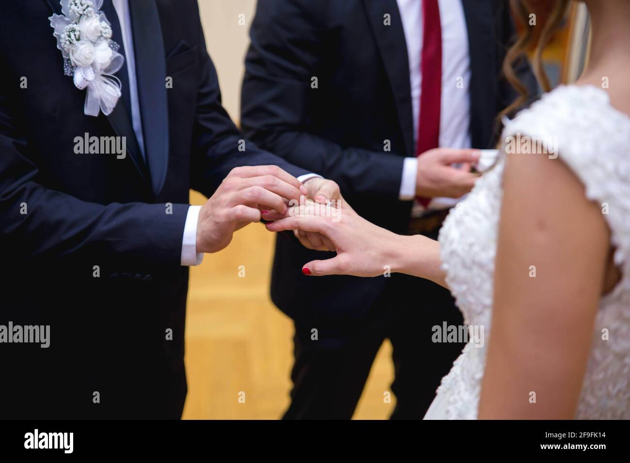 A groom putting a ring on a bride's finger during the wedding ceremony