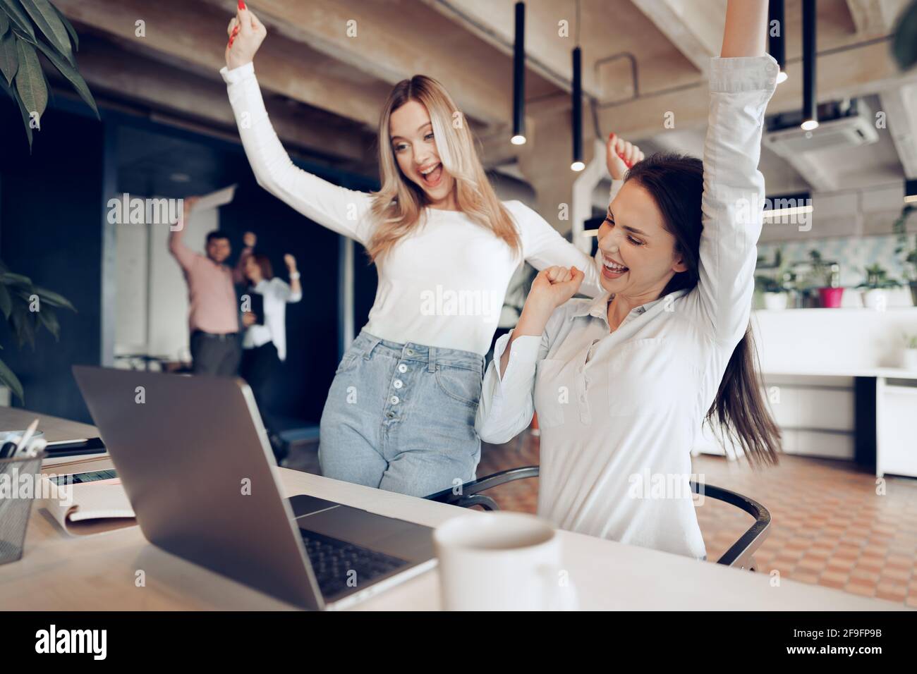 Two young happy businesswomen celebrating project success in office ...