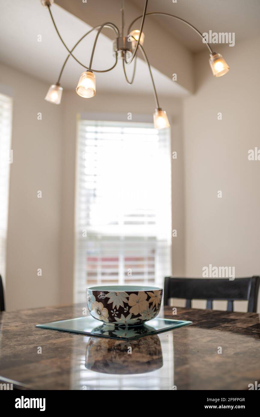 A decorative bowl on a kitchen table under a stylish chandelier in an apartment Stock Photo
