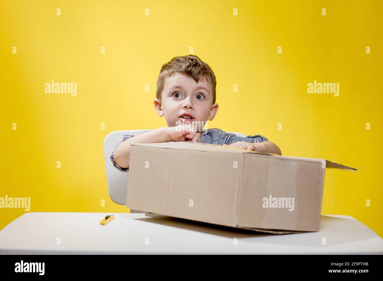 Surprised boy looking opening a box and gasping in surprise seeing the  content of the box while recording an unboxing vlog Stock Photo - Alamy
