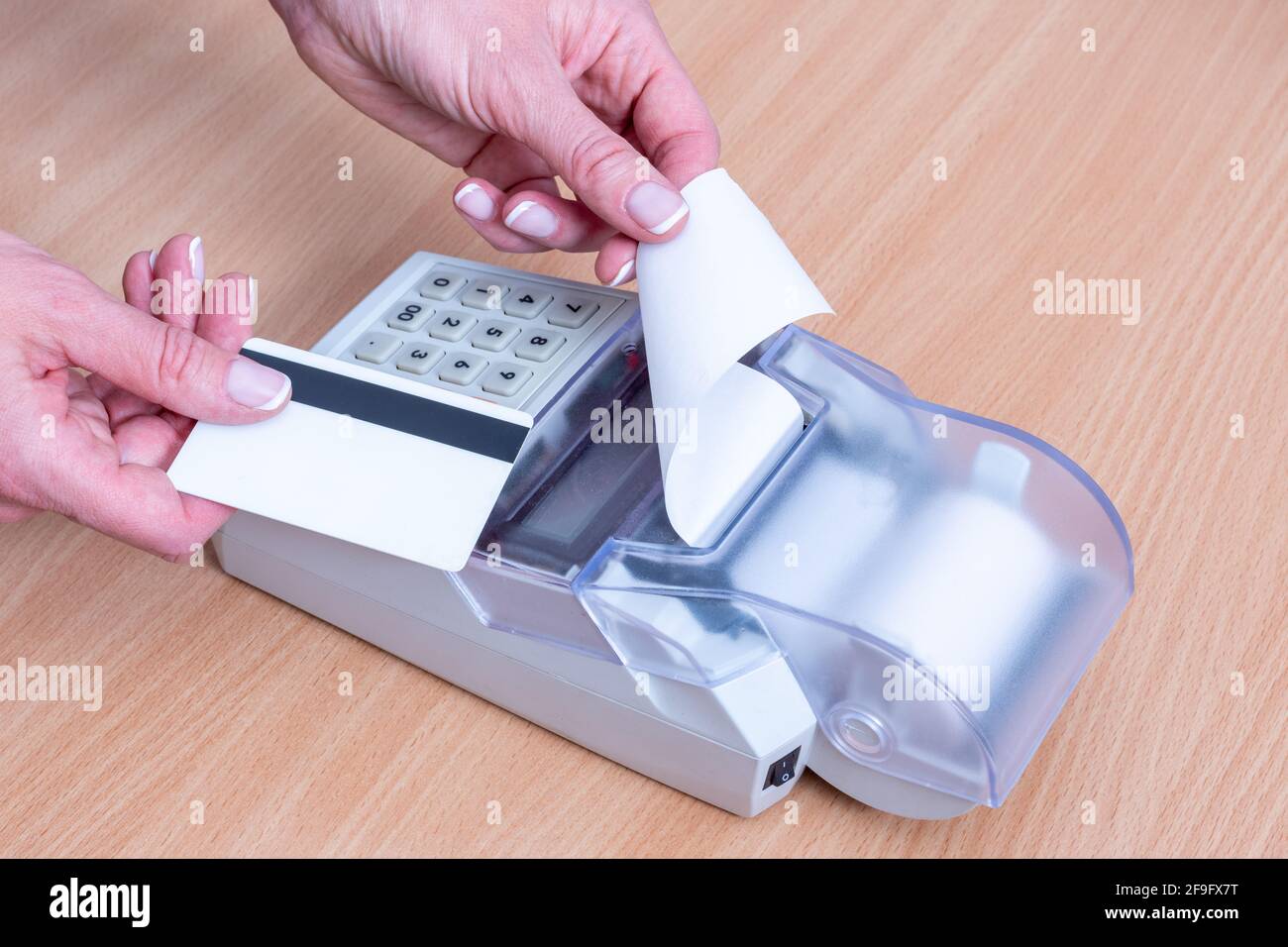 Business and financial concept. Close-up of hand holding a bank card above the cash register to pay for a purchase and issuing a check for payment on Stock Photo