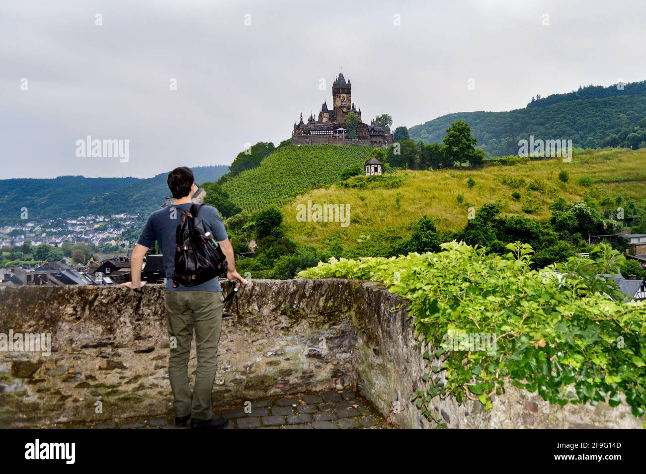 A back view of a young male tourist with a backpack visiting Cochem ...