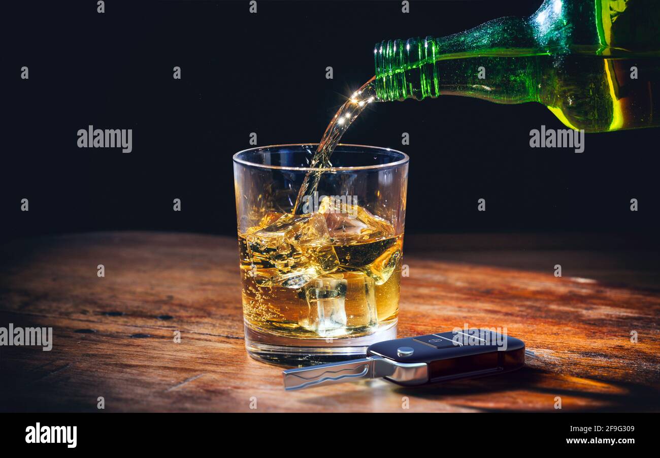 Drinking and driving concept. Car key and whiskey  glass and bottle on a wooden bar counter background. 3d illustration. Stock Photo