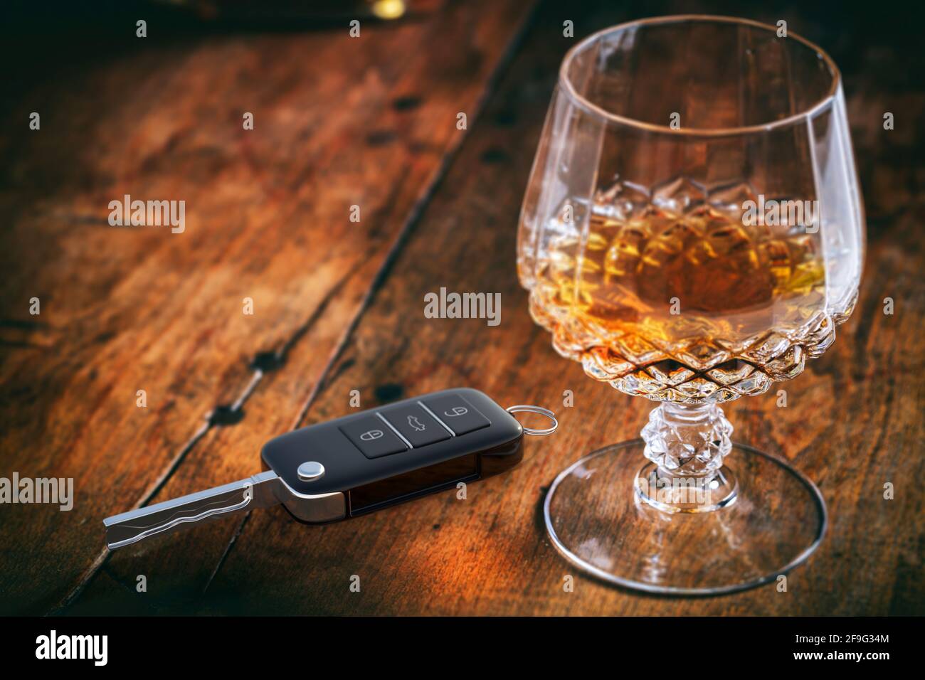 Alcohol drinking and driving concept. Car key and brandy glass on a wooden bar counter background. 3d illustration. Stock Photo