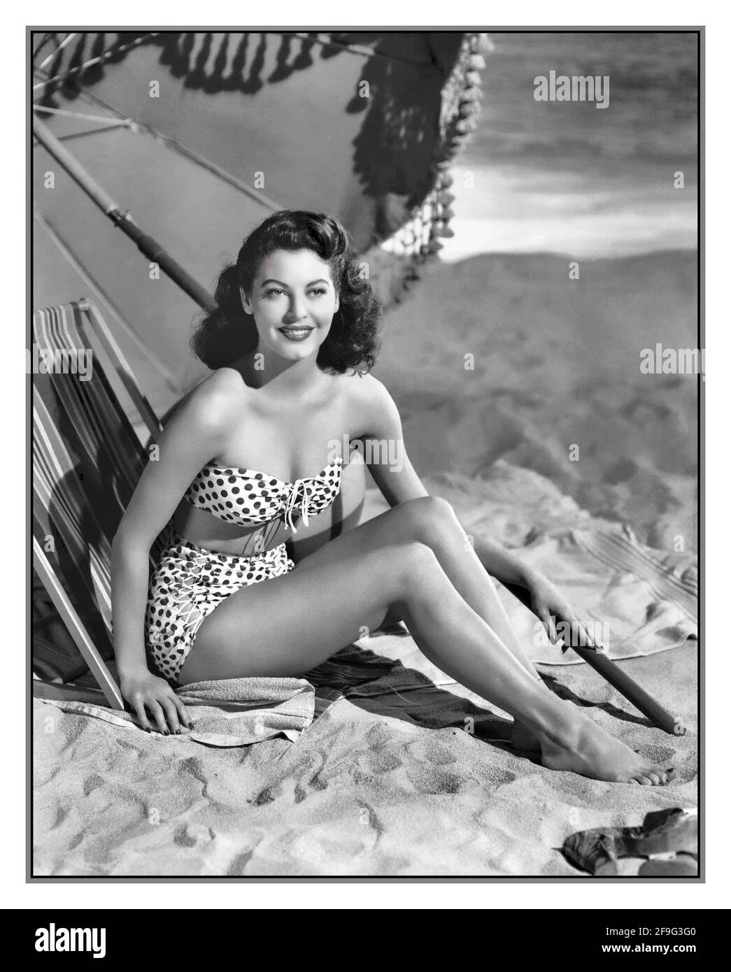 AVA GARDNER 1940’s Vintage 1940's Hollywood Actress Ava Gardner lounges on the studio set beach in a polka dot bikini 1944 Stock Photo