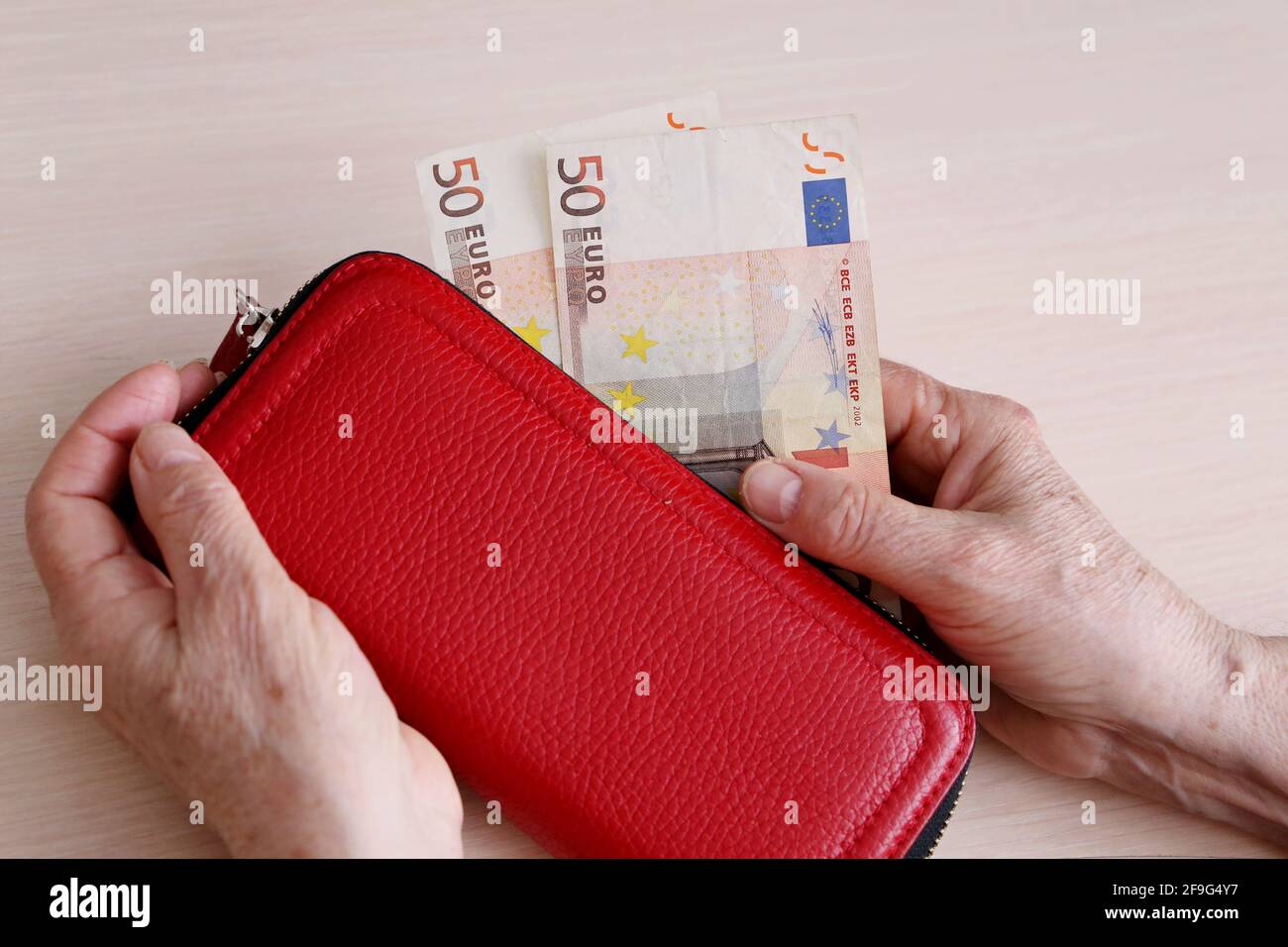 Elderly woman takes out a euro note from her wallet. Concept of pension payments, savings at retirement, pensioner with money Stock Photo