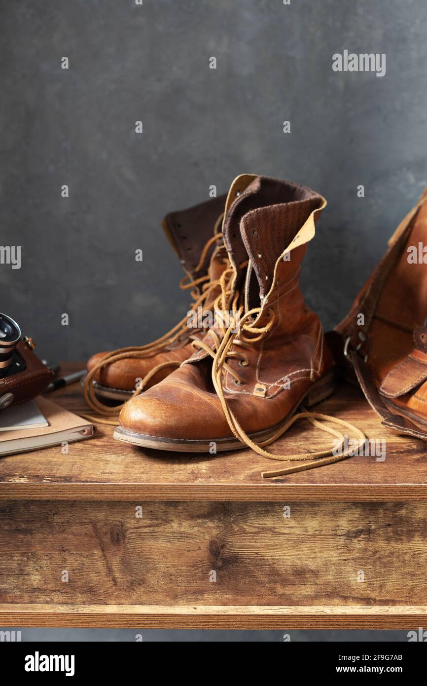 old leather travel vintage boots shoes and bag at wooden table, with wall background texture Stock Photo
