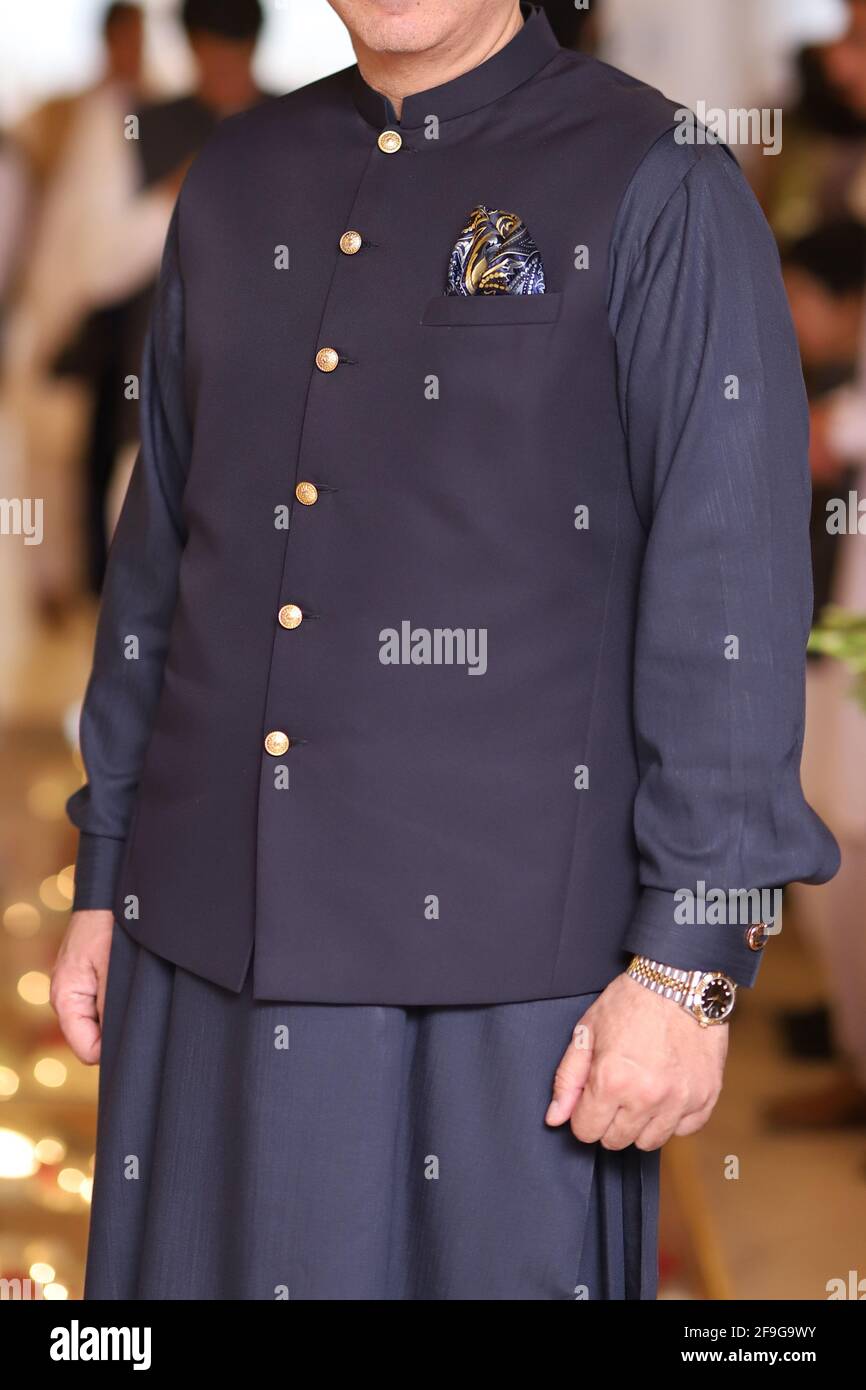 A man wearing Pakistani traditional dress shalwar kameez and waistcoat with  golden buttons and pocket square Stock Photo - Alamy
