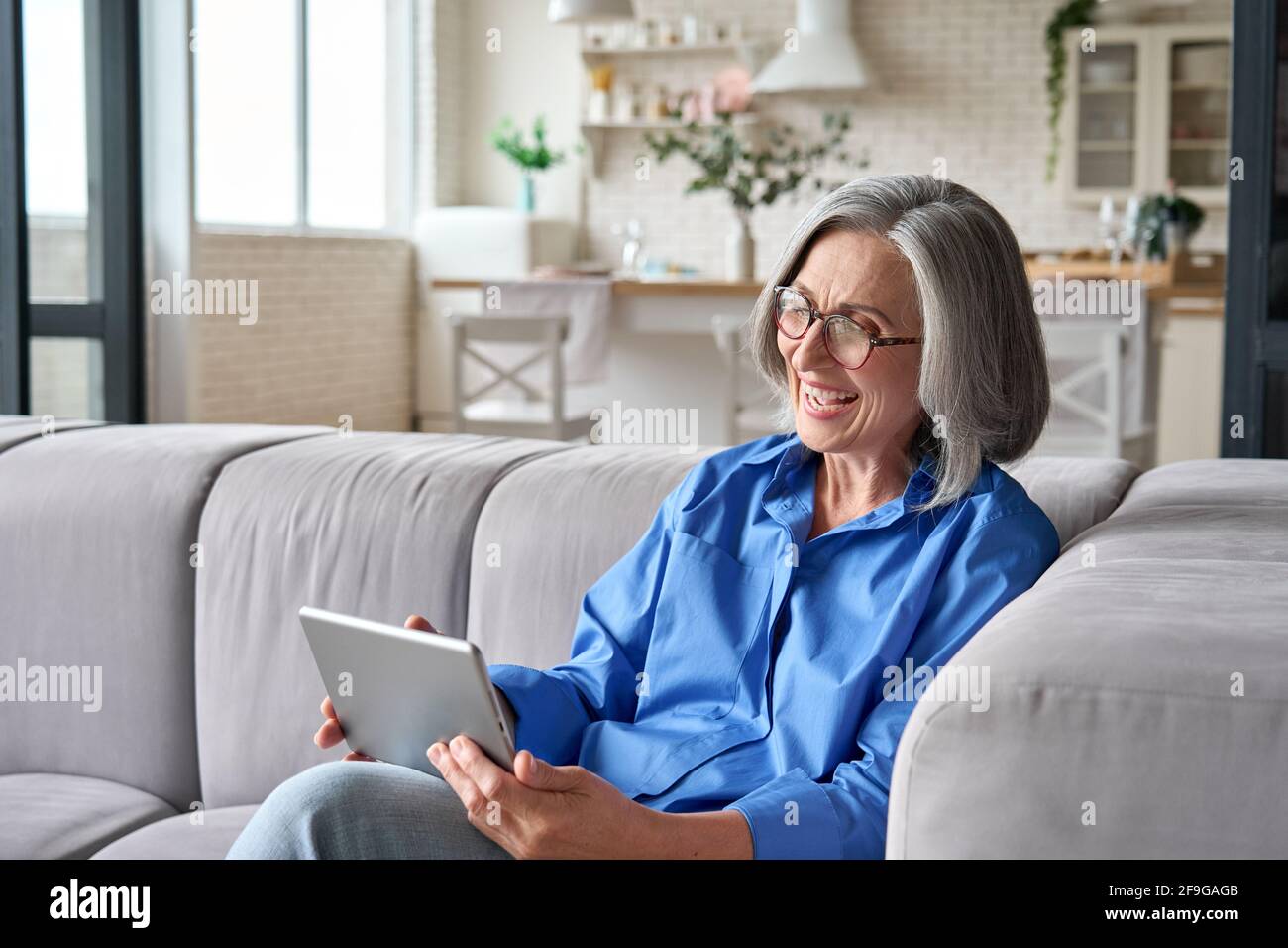 Senior older woman at home at video meeting with family friends on tablet. Stock Photo