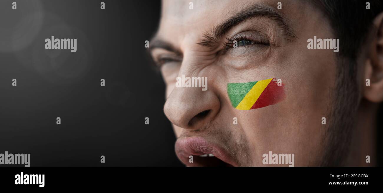 A screaming man with the image of the Congo national flag on his face Stock Photo