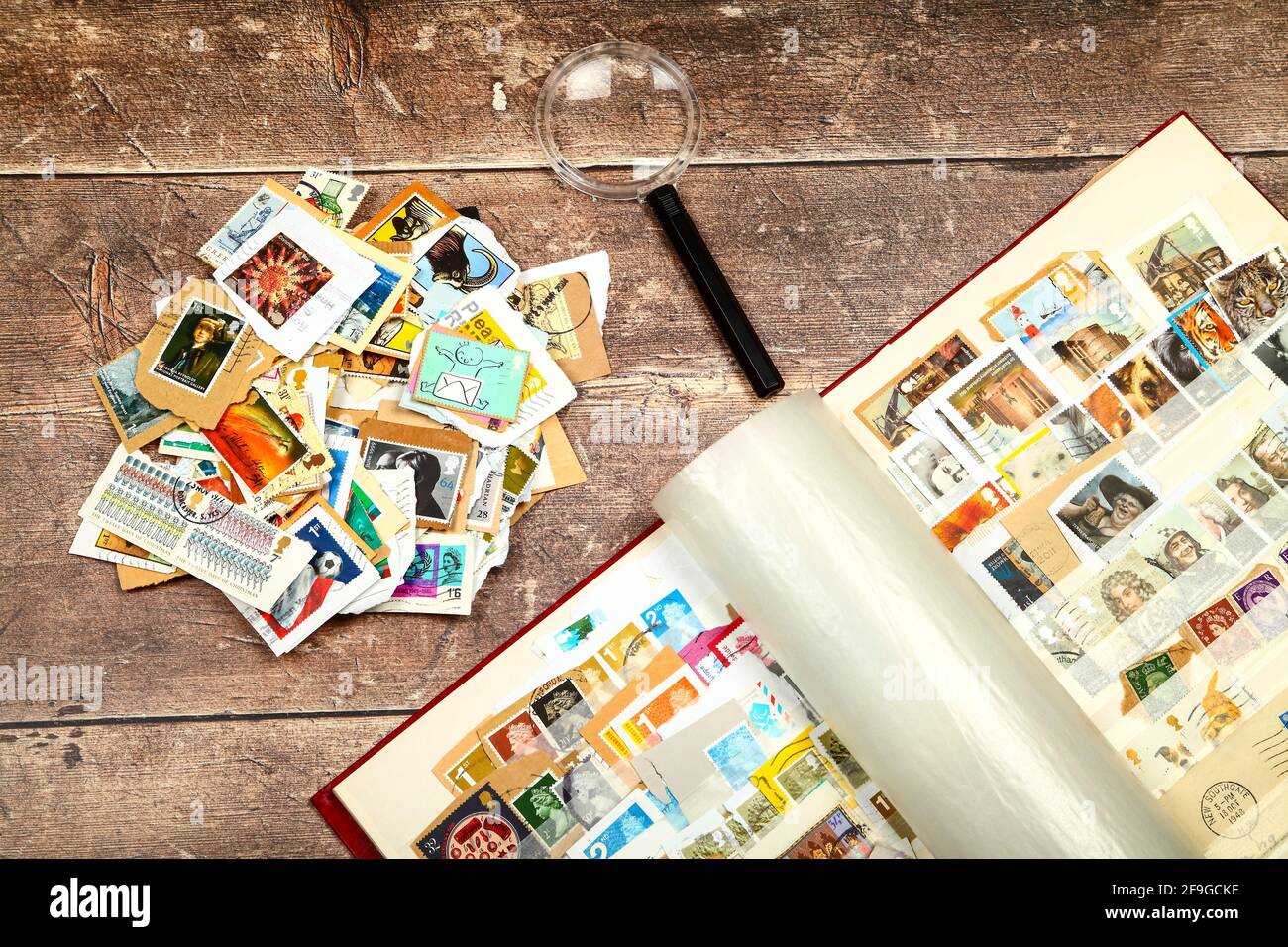 Stamp album full of used British postage stamps laid on a rustic wooden table top Stock Photo