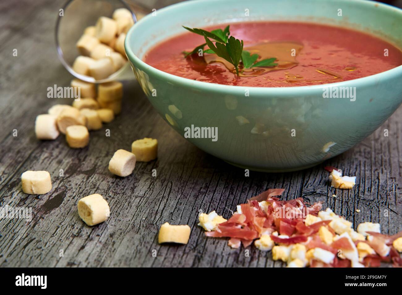 Close-up view of Andalusian gazpacho bowl with parsley and extra virgin olive oil, accompanied by croutons, Serrano ham and chopped boiled egg. Concep Stock Photo
