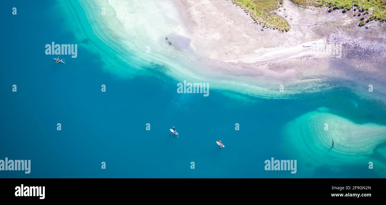People on a standup paddle and kayak on the shore of Plansee, Reutte