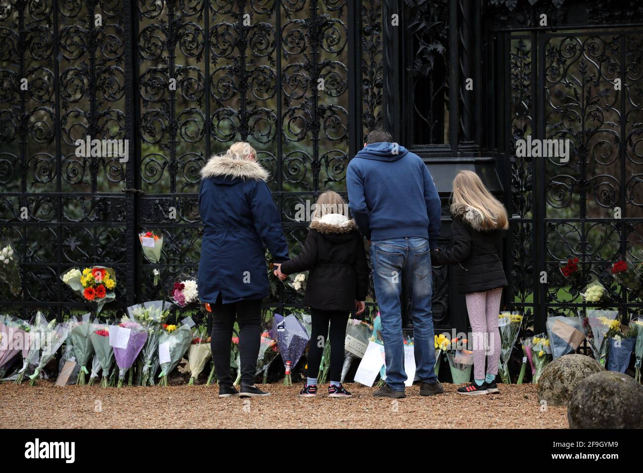 Sandringham, UK. 10th Apr, 2021. A family looks at flowers in front of The Norwich Gates as Sandringham is very sombre the day after Prince Philip, Duke of Edinburgh, passed away. People have laid floral tributes outside The Norwich Gates, at Sandringham House, Norfolk, which is the winter retreat of Queen Elizabeth II. Prince Philip has spent much of his time in the Sandringham area since his retirement in 2017. Credit: Paul Marriott/Alamy Live News Stock Photo