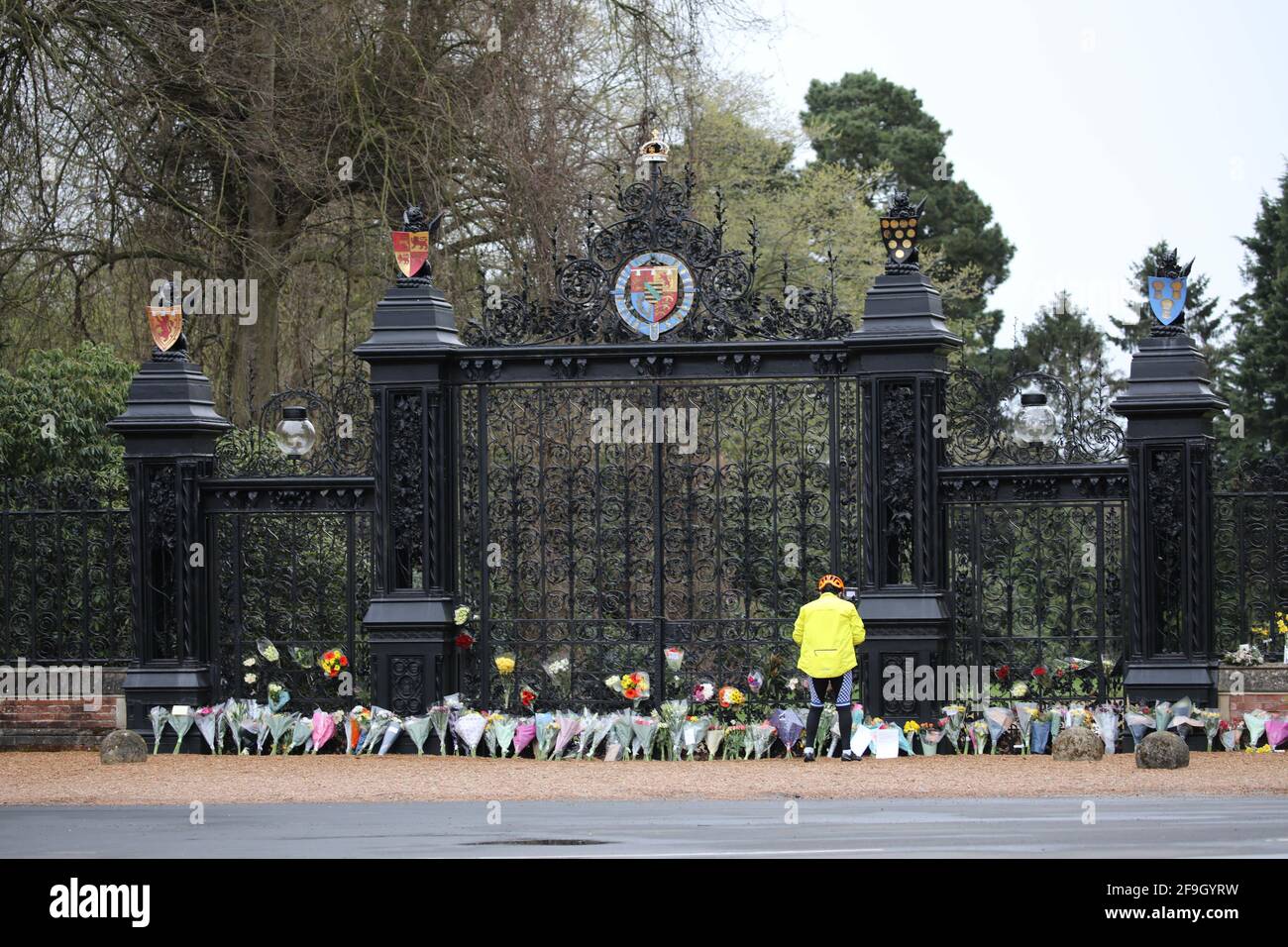 Sandringham, UK. 10th Apr, 2021. A person looks at flowers in front of The Norwich Gates as Sandringham is very sombre the day after Prince Philip, Duke of Edinburgh, passed away. People have laid floral tributes outside The Norwich Gates, at Sandringham House, Norfolk, which is the winter retreat of Queen Elizabeth II. Prince Philip has spent much of his time in the Sandringham area since his retirement in 2017. Credit: Paul Marriott/Alamy Live News Stock Photo