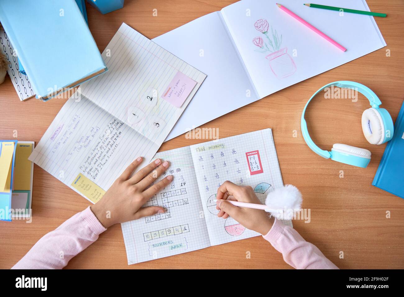 Table top view of child hands writing doing homework on math at home. Stock Photo