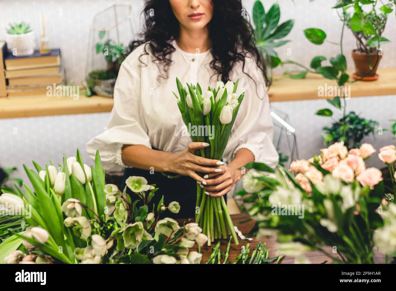 Attractive young woman florist is working in a flower shop Stock Photo ...