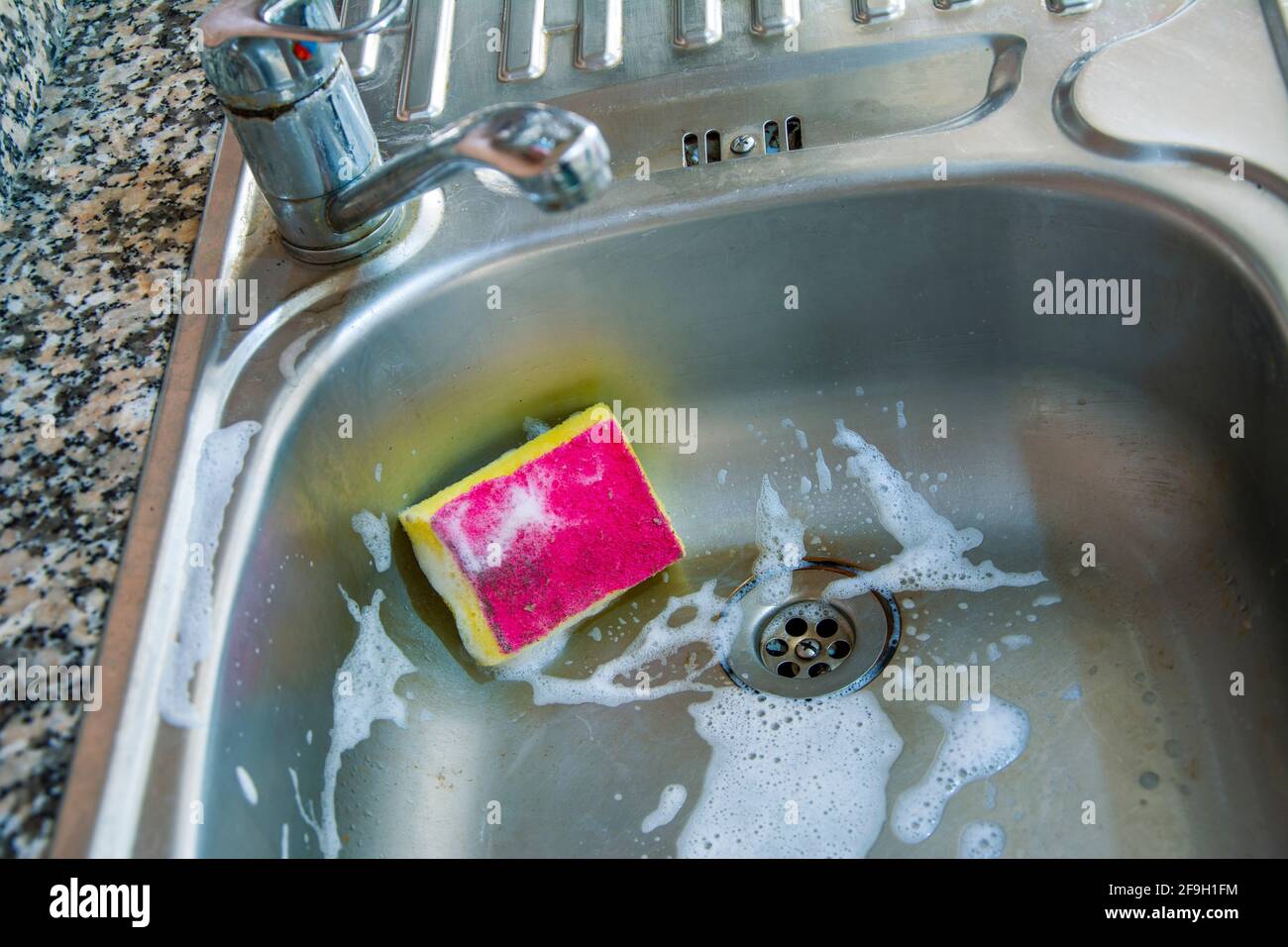 A sponge in the foamy and dirty sink Stock Photo