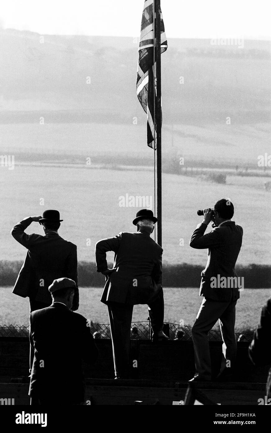 UK, England, Devonshire, Buckfastleigh, 1972. Point-to-Point races were held at  Dean Court on the Dean Marshes, close to the A38 between Plymouth and Exeter. Two stewards wearing black bowler hats  and other spectators watching a race under The Union Jack or Union Flag of the UK. Stock Photo