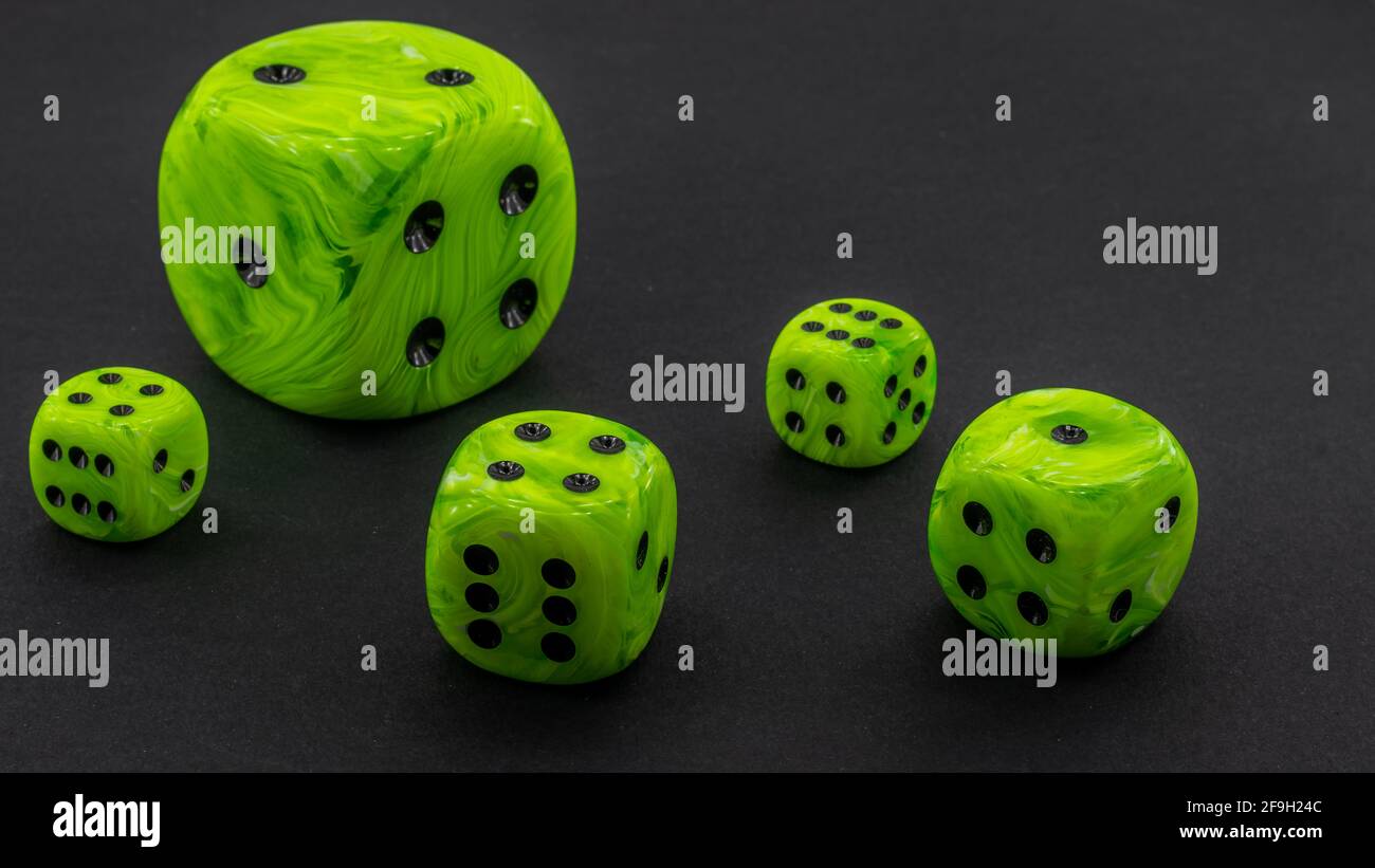 green dice with different size on a black background Stock Photo