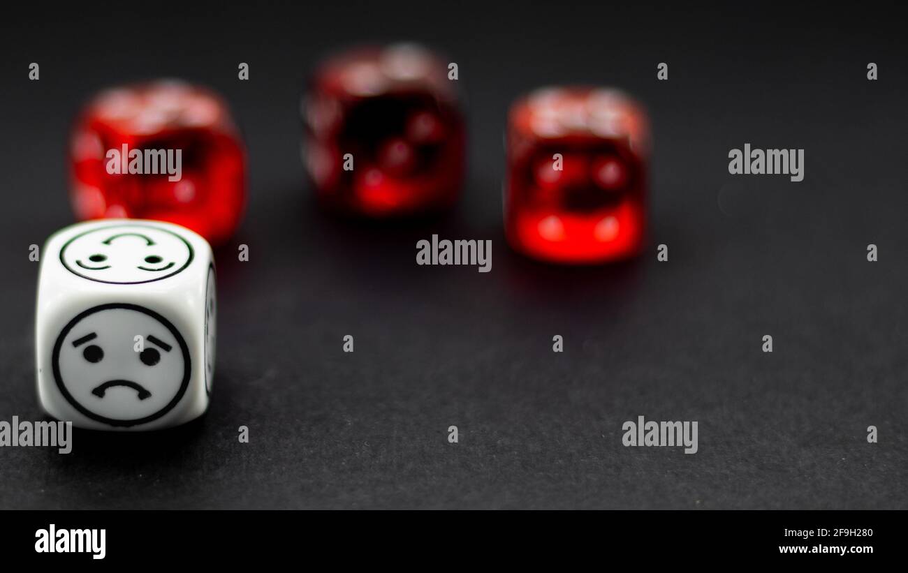 white dice with emoticon markers and red dice in the background blurred Stock Photo