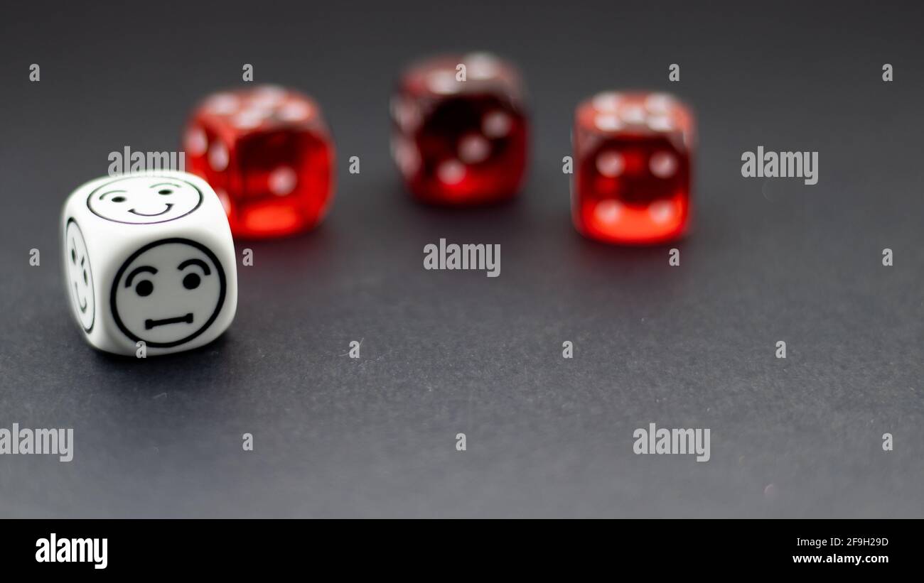 white dice with emoticon markers and red dice in the background blurred Stock Photo