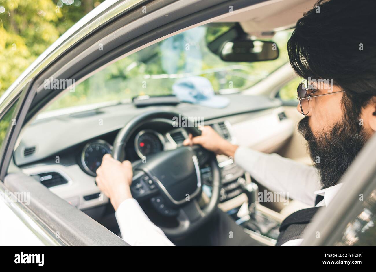 Stylish and successful Indian in a stylish suit driving a luxury car