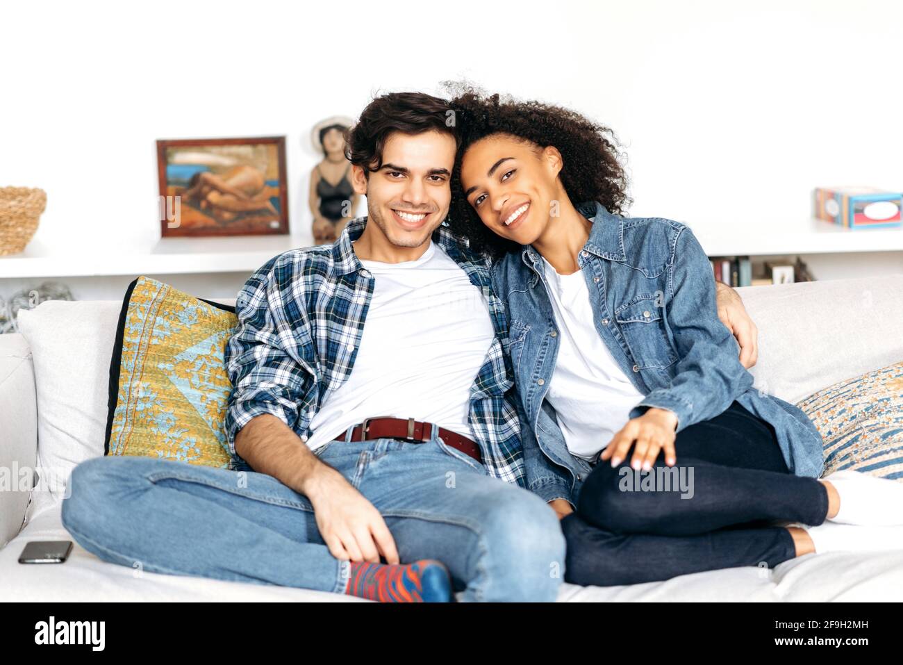 Joyful Happy Multiracial Couple In Love Sit On A Sofa African American Curly Girl And Mixed
