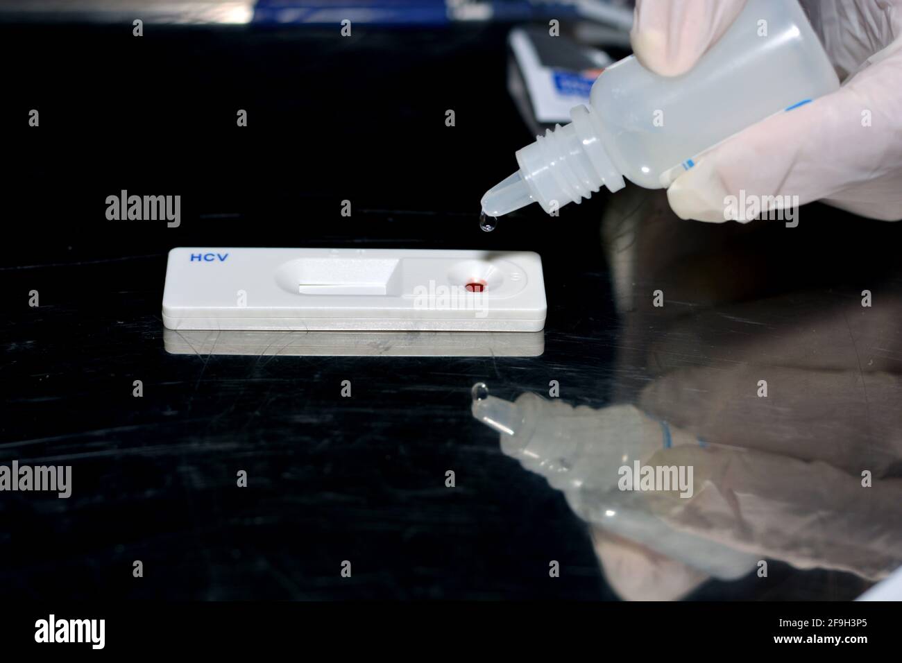 a medical personnel putting a reagent on blood drop inside a rapid test for Hepatitis C kit cassette for rapid diagnosis of viral infection Stock Photo