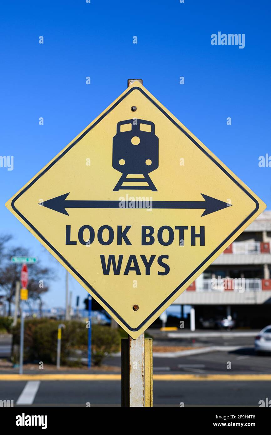 Look both ways sign with a two headed arrow and a train on railroad track in yellow and black.  This warning sign is in Edmonds, Snohomish County Stock Photo